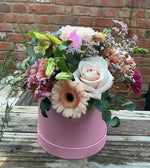 Pink and cream flowers that include roses in what could be a pink hat box that would be an ideal gift for Mother's Day