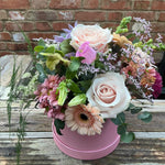 Pink and cream flowers that include roses in what could be a pink hat box that would be an ideal gift for Mother's Day