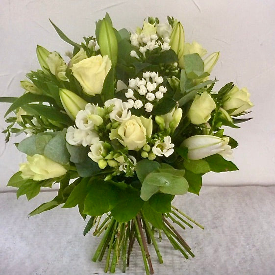 A beautiful bouquet of pure white flowers including white Lilies, Roses, Bouvardia, Freesias, Eustoma complemented with a selection of foliage. Hand tied, aqua packed and presented in a gift bag.